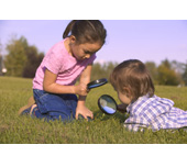 Picture of a girl and boy looking through magnifying glasses