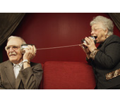 Picture of a man and a woman using two cans and a string as a telephone